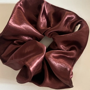Macro detail of high-end deep brown satin scrunchie with elegant pleated fabric texture