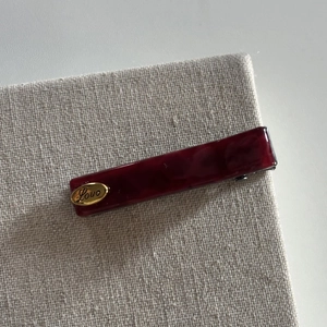 Detailed close-up of dark red marble acetate hair clip with a golden Love engraving