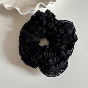 Macro detail of the elegant black lace hair scrunchie with delicate ruffled floral edges