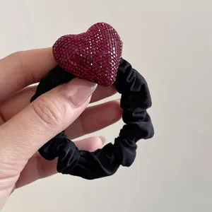 Elegante elastico per capelli nero con un ciondolo a cuore scintillante di strass rossi
