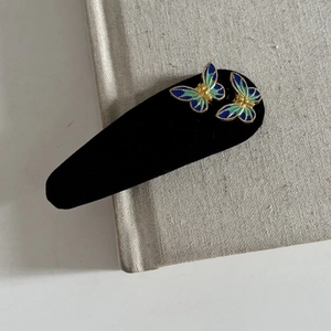 Vintage velvet butterfly hair clip with blue and green enamel gradient on book