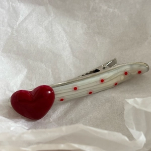 Detail of red heart duckbill hair clip with pearl white base and polka dot patterns