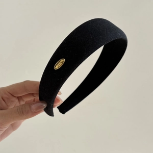 Elegant black thick sponge headband with a golden metal tag and refined woven fabric