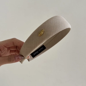 Minimalist oatmeal beige fabric wide headband featuring a vintage gold metal logo tag