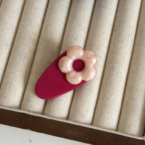 Détail d'une pince à cheveux fleur nacrée rose sur un plateau en velours beige