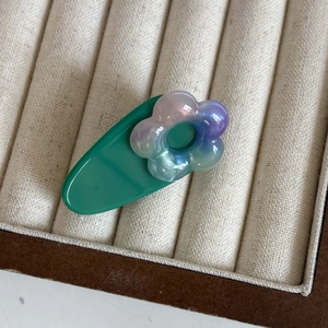 Détail de la pince à cheveux fleurie en acétate dans son coffret à bijoux en velours beige