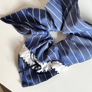 Detail of navy blue striped hair scrunchie with white lace edges and black ribbon bow