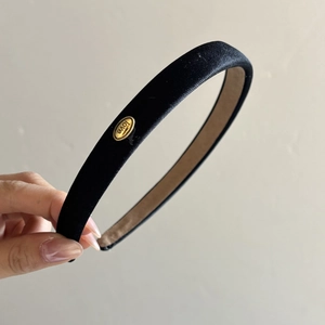 Detailed shot of black mercerized fabric headband with a golden love logo plaque