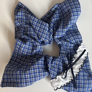 Detail of blue plaid bow scrunchie with white lace edges and a black ribbon accent
