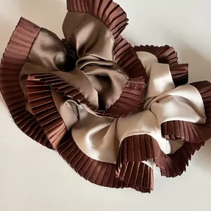 Detail of oversized pleated scrunchie in coffee and beige satin with striped texture
