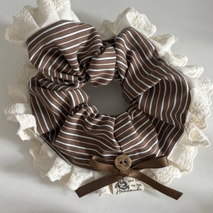 Détail d'un chouchou à rayures marron avec bordure en dentelle et bouton en bois fait main