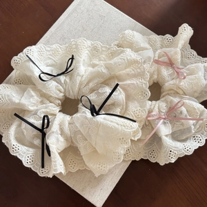 Sweet lace scrunchie hair ties with ribbon bows on a book and wooden surface