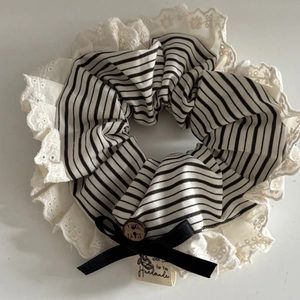 Détail du chouchou en dentelle rayée avec bouton en bois et étiquette fait main