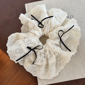 Elegant cream lace scrunchie featuring black velvet bows on a wooden vintage surface