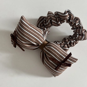 Vue détaillée d'un chouchou en dentelle à rayures marron et blanc avec grand nœud et ruban