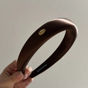 Detail view of handmade brown satin padded headband with gold label and Korea design