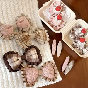 Detail of pink plaid bow hair clips with ruffle edges and cute faux cherry accents