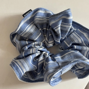 Detailed macro view of the blue and white striped cotton scrunchie with fashion label tag