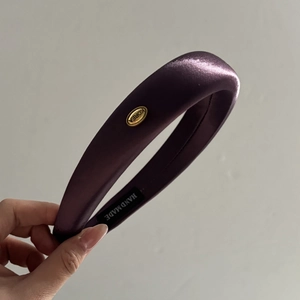 Detail of dark purple satin headband showing the gold Korea logo and handmade label