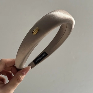 Detailed view of handmade thick champagne silk headband with gold Korea metal label