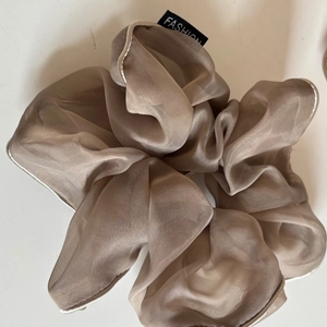 Detailed texture of champagne organza scrunchie with fashion label and stitched edge
