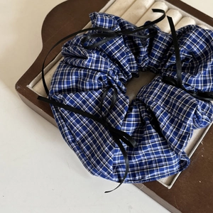 Vue détaillée d'un chouchou à carreaux bleus et blancs avec un nœud en ruban de soie noir