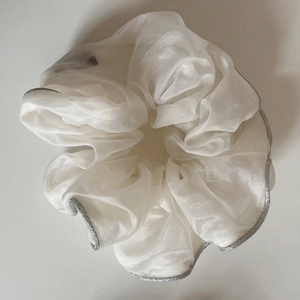 Detail of white organza scrunchie with elegant silver tinsel edges and ruffled texture
