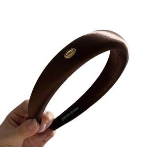 Brown silk padded headband with a gold metal label and smooth glossy finish