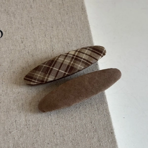 Detail of sweet handmade hair clips featuring brown plaid fabric and suede finishes