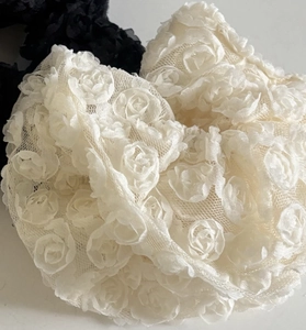 Detailed macro view of black and white lace mesh scrunchies with 3D rose flower decorations