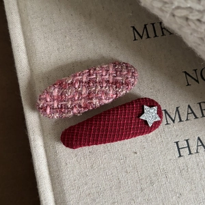 Detailed close-up of pink tweed and red fabric hair clips with a silver star embellishment