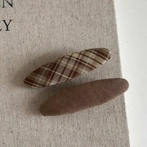 Close-up of brown plaid and solid fabric hair clips showing woven cotton texture