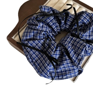 Chouchou à carreaux bleus avec nœuds noirs sur une boîte à bijoux en bois naturel