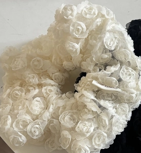Detailed macro view of white lace scrunchie with 3D rose flowers and mesh texture