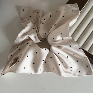 Vista dettagliata dell'elastico per capelli beige a pois con ricamo a ciliegia in raso