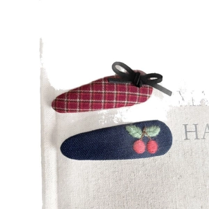 Plaid bow hair clips and cherry embroidery BB hairpins on a rustic fabric background