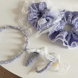 Dettaglio degli accessori per capelli color lavanda con pizzo, perle e tessuto a bolle