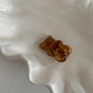 Pince à cheveux ours ambré en résine avec clip doré sur une assiette blanche