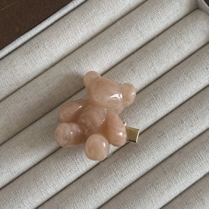 Gros plan d'une pince à cheveux ours rose marbré sur un organisateur en lin beige