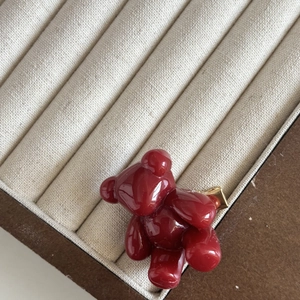Détail macro d'une pince à cheveux ours rouge vin translucide sur une boîte blanche