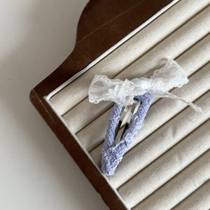 Dettaglio del fermaglio per capelli in pizzo viola con fiocco bianco in scatola di legno