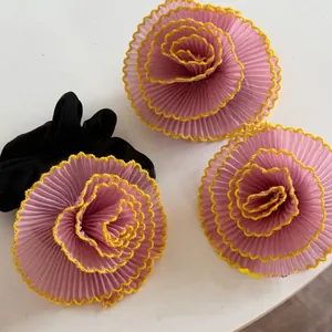 Vue détaillée de chouchous à fleurs plissés roses et jaunes sur un fond blanc uni