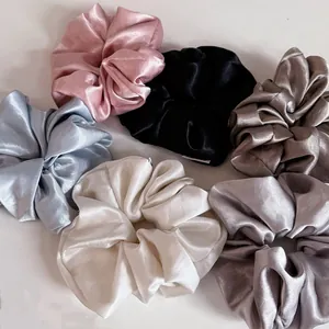 Close-up of assorted satin scrunchies in cream, black, pink, and blue with silky luster