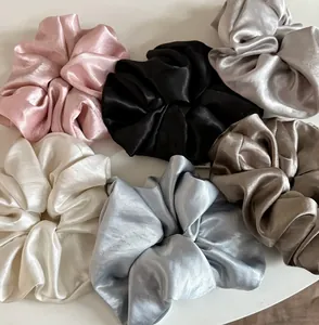 Close-up of 6 oversized satin silk scrunchies in cream, black, silver, and blue tones