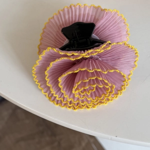 Détail de la pince à cheveux avec fleur en mousseline rose plissée et bords jaunes