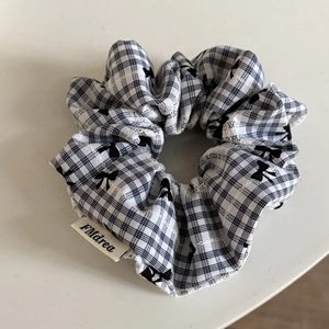 Gros plan d'un chouchou à carreaux noir et blanc avec motif nœud et étiquette tissée FMdrea