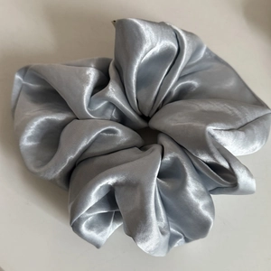 Close-up of silver-grey satin scrunchie showing glossy fabric texture and pleated details