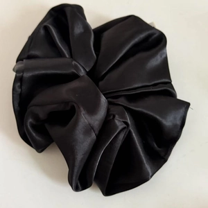Macro shot of large black satin scrunchie with smooth texture and soft glossy finish