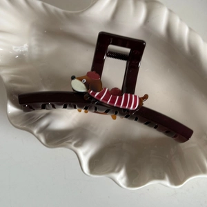 Detailweergave van de donkerbruine teckel haarklem met een schattig cartoon hondenfiguur