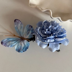 Fermaglio per capelli con farfalla blu e viola e fiori su uno sfondo minimalista